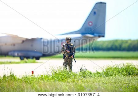 Boboc, Romania - May 22, 2019: Romanian Army Soldier Patrols A Military Air Base, With An Alenia C-2