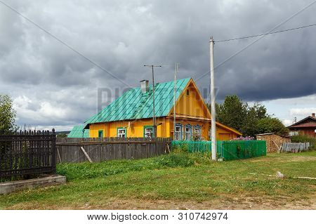 Russian Village In Summer. View Of The Brighty Painted Wooden Residential House Before A Thunder Sto