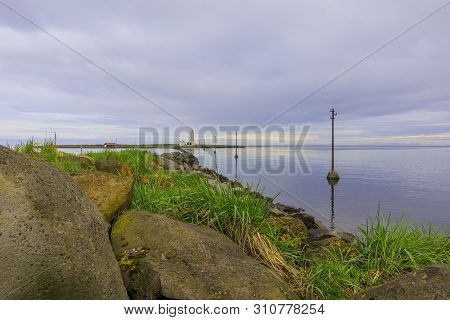 Electricity Pylons In The Water To The Island Of Grotta Near Reykjavik In The Morning With Clouds In
