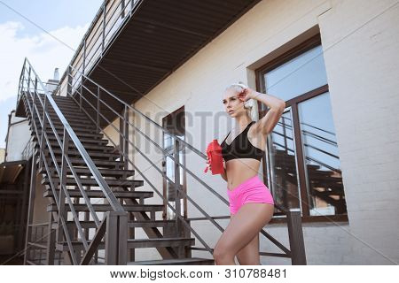 A Young Athletic Woman In White Headphones Working Out Listening To The Music On A Stairs Outdoors. 