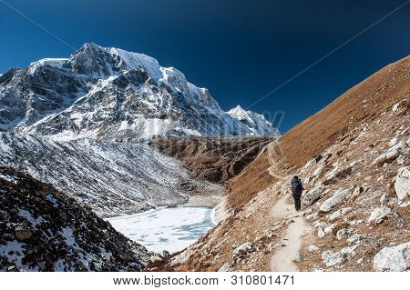 Young Woman And Man With Backpacks Walking To The Pass On Manaslu Circuit With View Of Mount Manaslu
