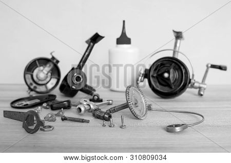 A Fishing Spinning Reel As A Whole And A Second Similar Completely Disassembled. Black And White Ima