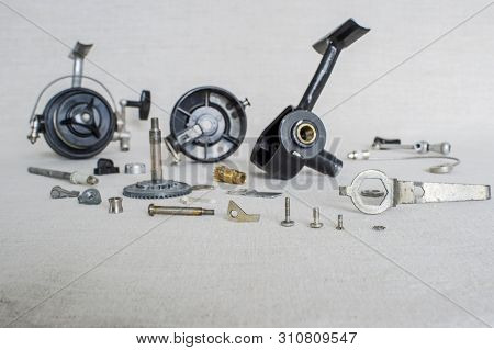 A Fishing Spinning Reel As A Whole And A Second Similar Completely Disassembled. Concept: Parts Of A