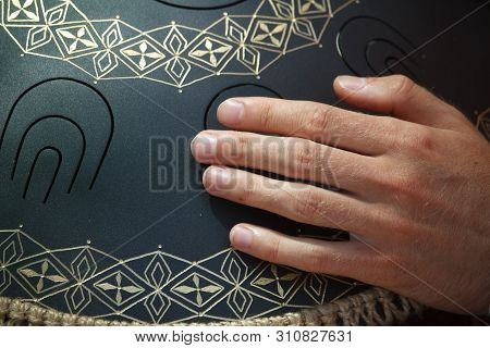 Close-up Of A Mans Hand Playing On Modern Musical Instrument Hand Pan Or Vadjraghanta Or Metal Tongu