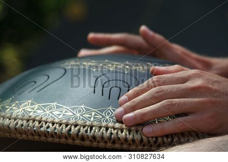 Close-up Of A Mans Hand Playing On Modern Musical Instrument Hand Pan Or Vadjraghanta Or Metal Tongu