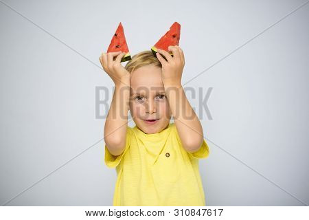 Frolicsome Caucasian 5 Year Old Boy Child In Yellow T-shirt Holding Two Pieces Of Red Watermelon Abo