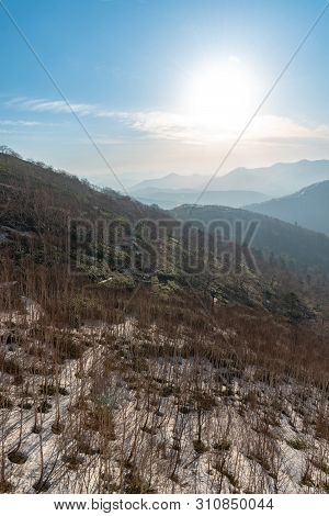 Panoramic View Of Beautiful Mountain Landscape, Snowy Mountain Peaks Covered By Forest With A Dark B