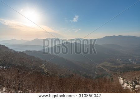 Panoramic View Of Beautiful Mountain Landscape, Snowy Mountain Peaks Covered By Forest With A Dark B
