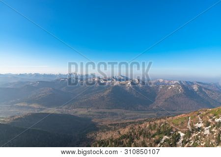Panoramic View Of Beautiful Mountain Landscape, Snowy Mountain Peaks Covered By Forest With A Dark B