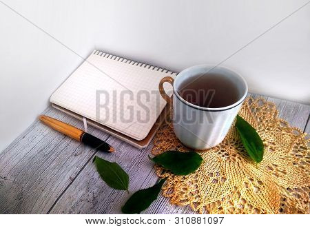 Flat Lay Desk With Golden Pen, Knitted Blanket Notebook And Cup Of Tea On Vintage Light Grey Wooden 