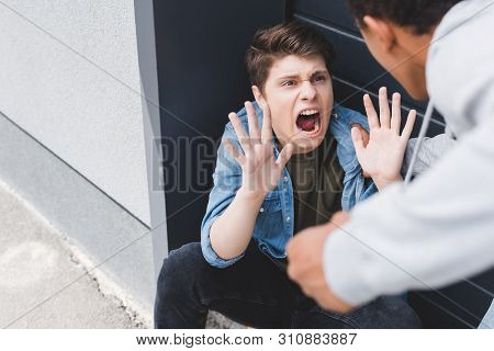 Selective Focus Of African American Boy Punching Scared And Yelling Boy