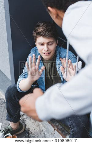 Selective Focus Of African American Boy Punching Scared Boy In Shirt