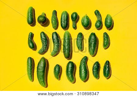Different Sizes Forms Cucumbers Pattern On A Light Yellow Background. Copy Space.
