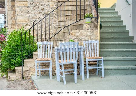 Table With Chairs Near The Stairs Leading Up To Cafe, Bar, Restaurant, Tavern. Building Exterior For