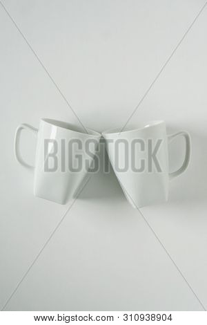 White Coffee Mugs On White Background Clinking In Cheers With Empty Copy Space