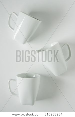 3 White Coffee Mugs On White Background Scattered With Empty Copy Space