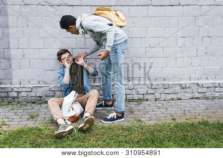 Angry And Brunette African American Boy Bulling Frightened Boy In Glasses