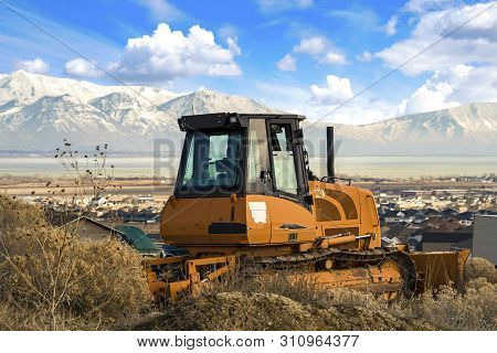 Yellow Loader On A Hill Overlooking Houses On A Residential Area In The Valley