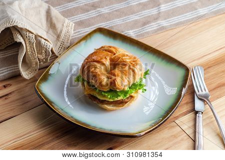 Sausage Egg And Cheese On Flaky French Croissant Roll With Romaine Lettuce