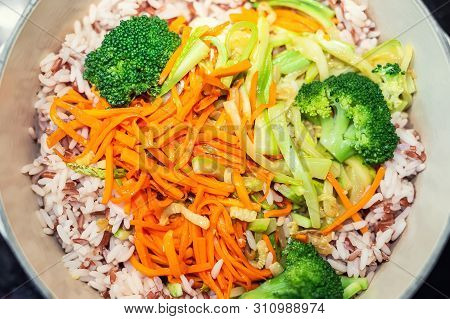 Brown Rice With Organic Unmixed Peeled Sliced Vegetables Cooking In Cast Iron Saucepan. Bright Brocc
