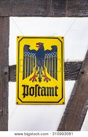 Old Historic Post Office Sign (postamt) At A Half Timbered Wall In Germany