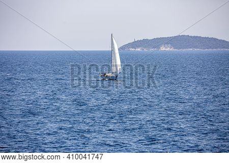 A Single White Sailing Boat In The Open Sea.