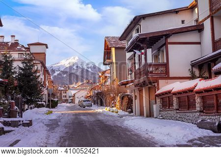 Bansko, Bulgaria Street View, Traditional Houses And Todorka Snow Mountain Peak In Bulgarian Ski Res
