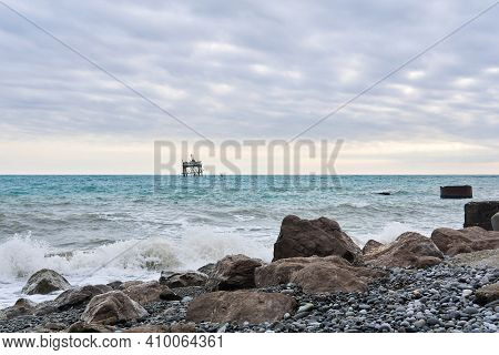 Winter Beach With Seascape And A Rickety Structure On The Stilts Of An Mariculture Farm In The Dista