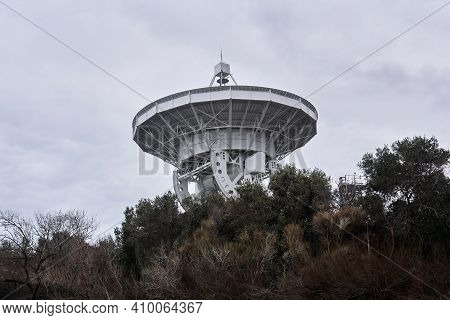 Mirror Of A Large Astronomical Radio Telescope, Aimed At A Cloudy Sky, Is Visible From The Trees