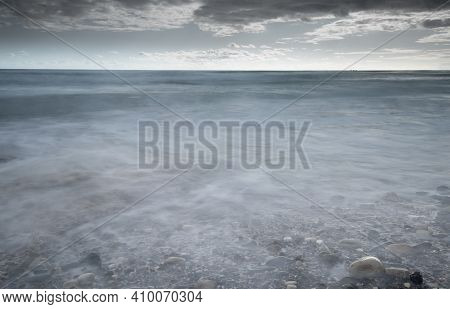 Seawaves Splashing To The Coast With Pebbles Against Stormy Dramatic Cloudy Sky. Wintertime, Longexp