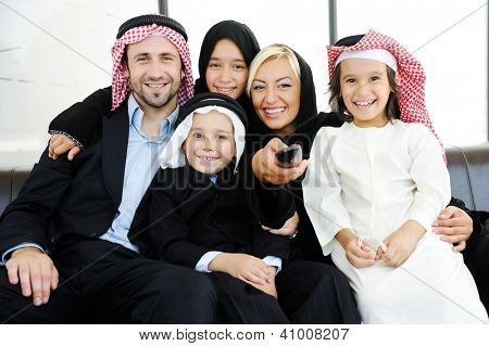 Arabic Muslim family father and mother with children watching television