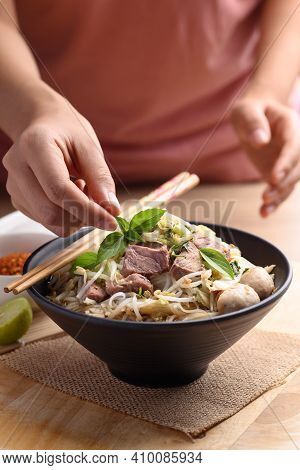 Rice Noodle Soup With Pork, Pork Ball And Vegetables In A Bowl Decorated With Basil Leaf By Woman Ha
