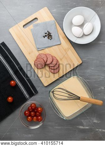 Black Whisk. Making An Omelet With Sausage And Cherry Tomatoes