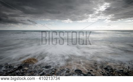 Seawaves Splashing To The Coast With Pebbles Against Stormy Dramatic Cloudy Sky. Wintertime, Longexp