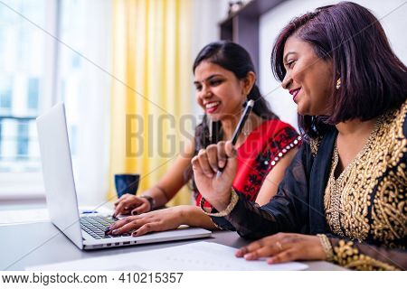 Two Indian Colleages Discussing Ideas Using A Tablet Computer At The Office