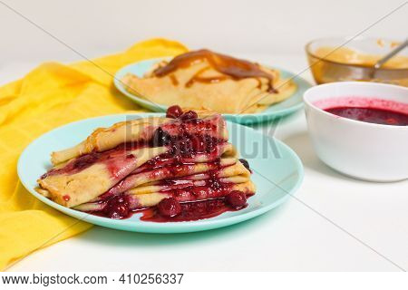 Blini Pancakes With Red Berry Jam Close-up On A Blue Plate On A Light Background . Traditional Russi