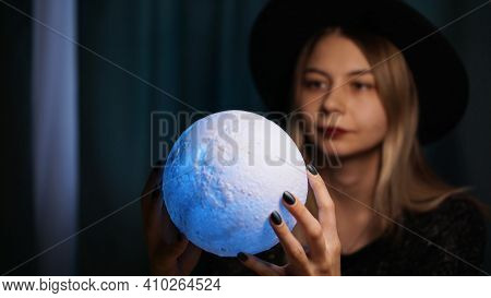A Young Woman Fortune Teller In A Hat Is Holding A Magic Ball. Beautiful Psychic Woman Is Guessing W