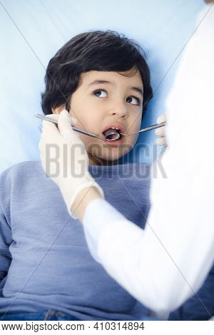 Little Arab Boy Sitting At Dental Chair With Open Mouth During Oral Checking Up With Dentist Doctor.