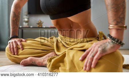 Young Tattooed Girl Practising Uddiyana Bandha Abdominal Lock While Sitting On Floor Mat At Home, Wi