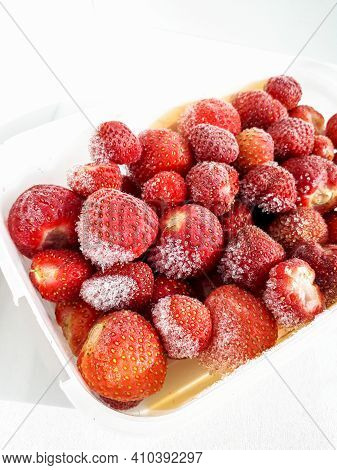 Macro Shot Of Frozen Strawberries With Frost On Them In A Plastic Container On White Background