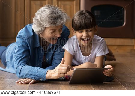 Overjoyed Senior Grandmother Have Fun Using Tablet With Granddaughter