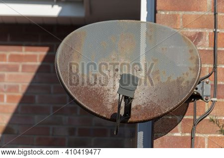 A Close Up View Of A Old Rusted Satellite Dish Attached To A Brick Wall