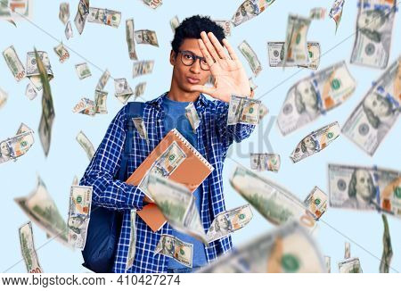 Young african american man wearing student backpack holding book doing stop sing with palm of the hand. warning expression with negative and serious gesture on the face.