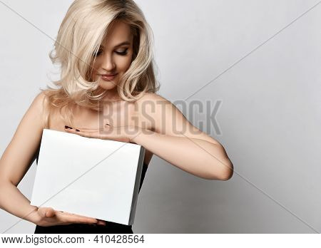 Portrait Of Young Positive Pretty Blonde Woman Standing And Holding White Paper Shites Or Empty Box 