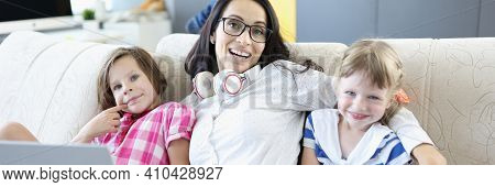 Smiling Woman Sitting With Laptop And Children On Couch. Business For Women At Home Concept
