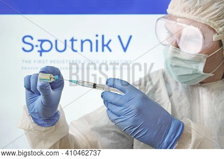 Doctor Prepares A Vaccine Against The Coronavirus Covid 19 On The Background Of The Sputnik V Logo.
