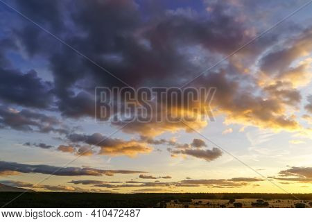 Sunset Landscape In The Field, Trees, Red Earth And Sky With Big Clouds In Blue And Orange Tones Of 