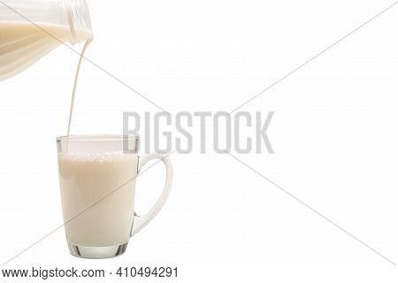 Milk Is Being Poured From A Bottle Into A Cup. Milk Splash.