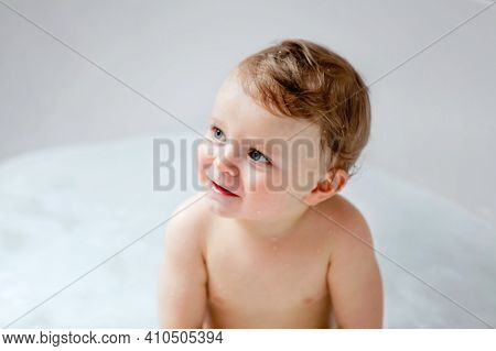Cute Adorable Baby Child Taking Bath In Bathtub At Home. Happy Healthy Boy Or Girl Playing, Splashin