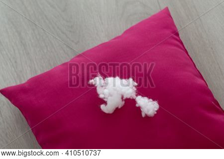 A Lump Of Pillow Filler Lies On A Red Cushion On A Light Wooden Table. Close-up. Selective Focus, Ho
